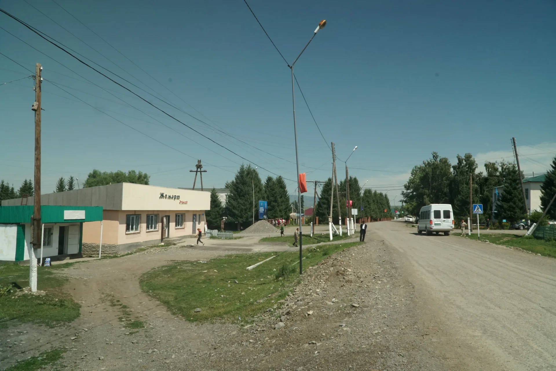 Village houses and yards in Saty, Kazakhstan, with mountain ridgelines of the Tian Shan visible behind the settlement.
