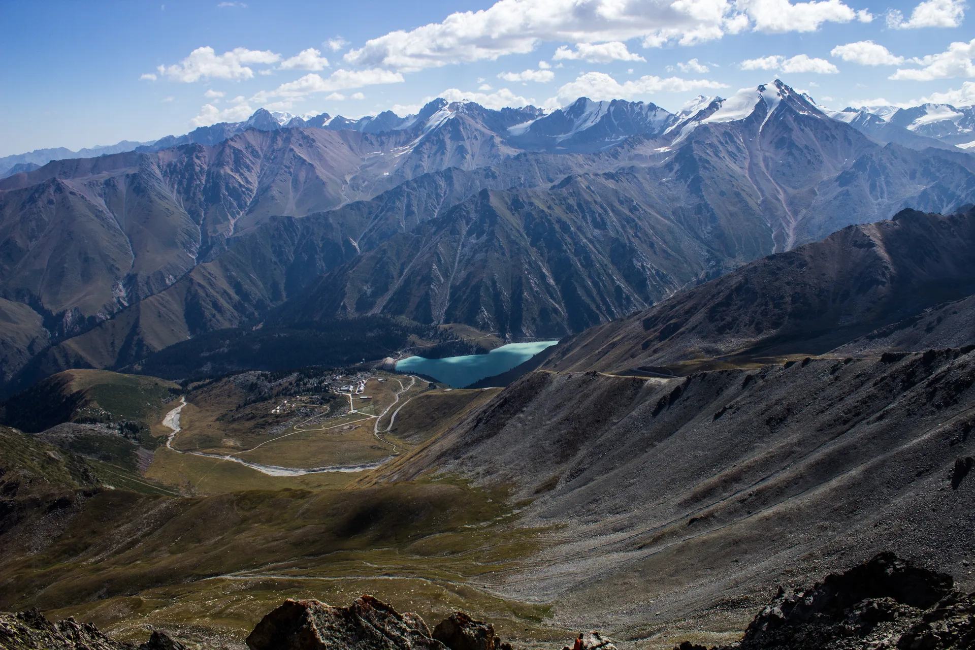 Big Almaty Lake seen from the mountain pass above, its turquoise water set against steep rocky slopes of Ile-Alatau National Park.