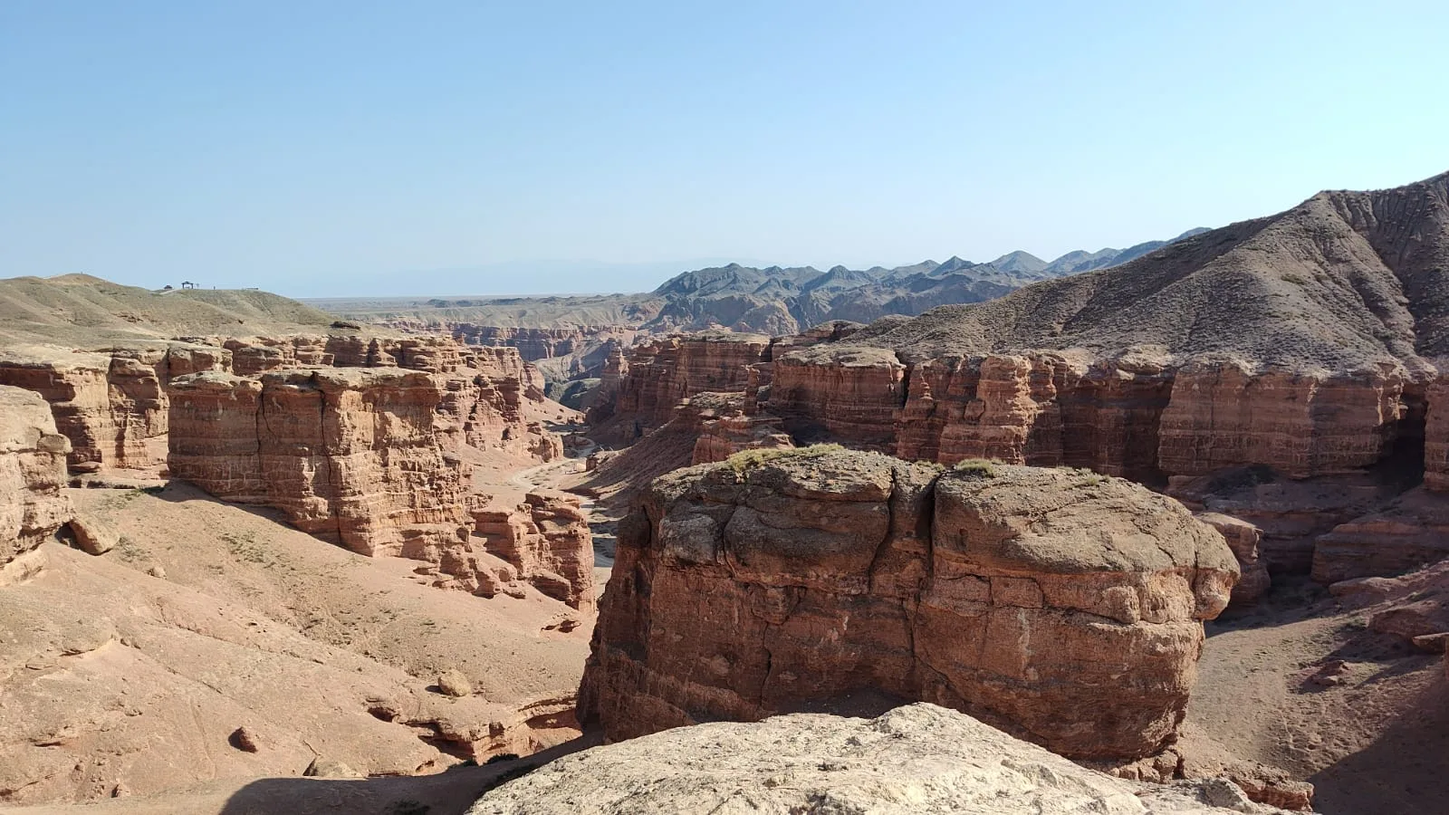 Red and ochre sandstone pillars of Charyn Canyon's Valley of Castles rising against a clear sky in Kazakhstan.