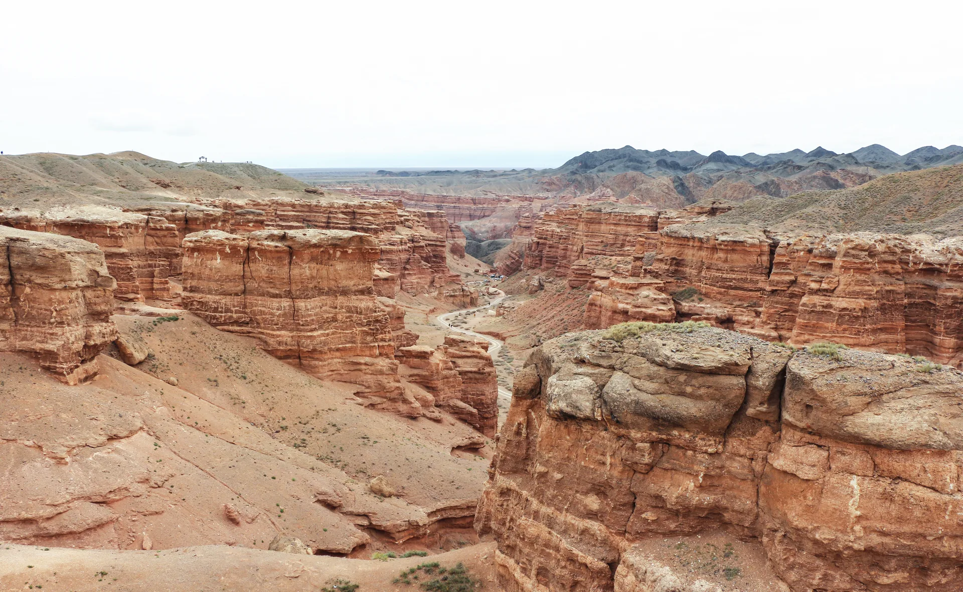 Eroded red and orange sandstone formations of Charyn Canyon's Valley of Castles under a blue sky.