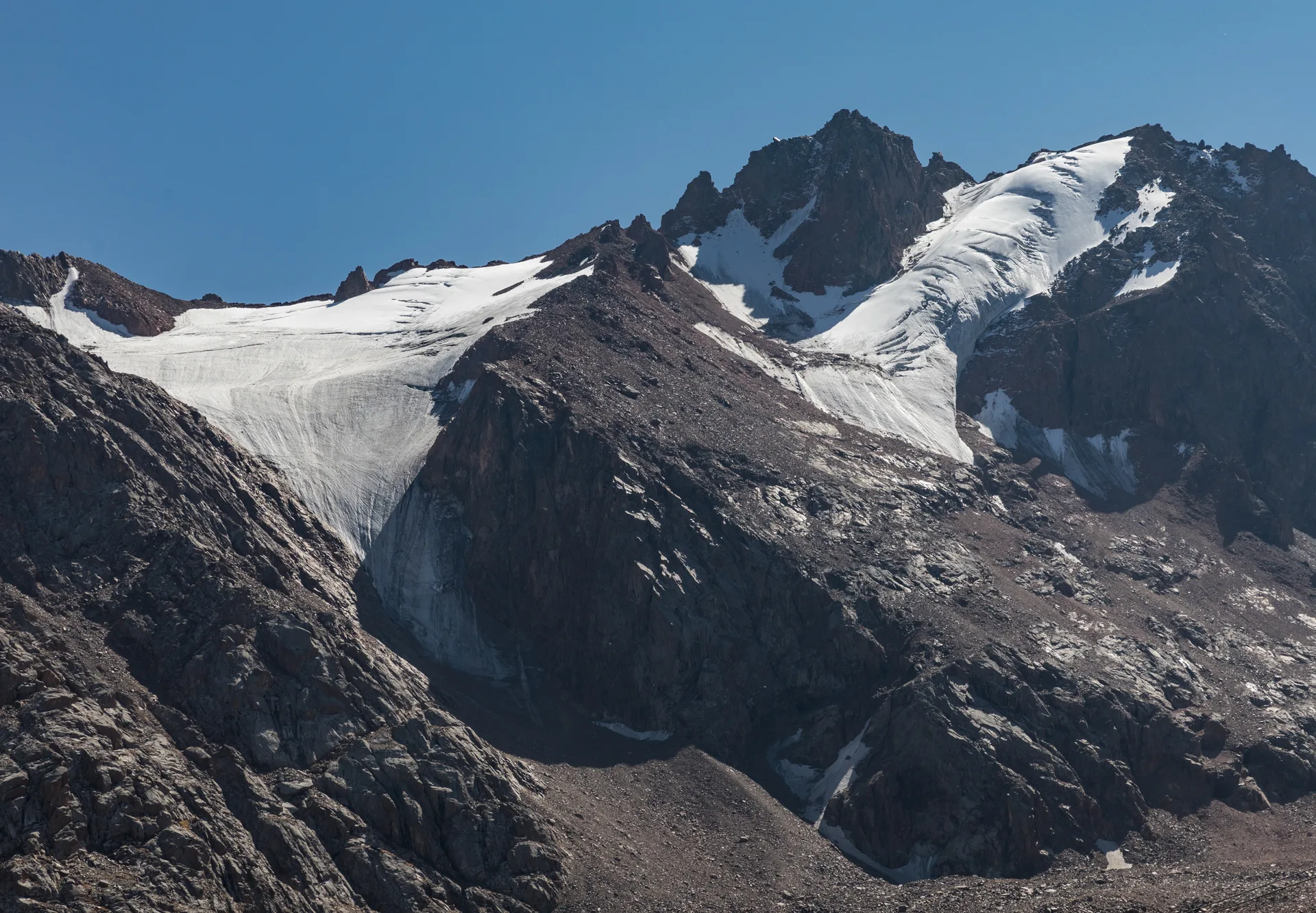 Snow-dusted peaks of the Ile-Alatau range above Shymbulak, seen from the alpine zone in September.