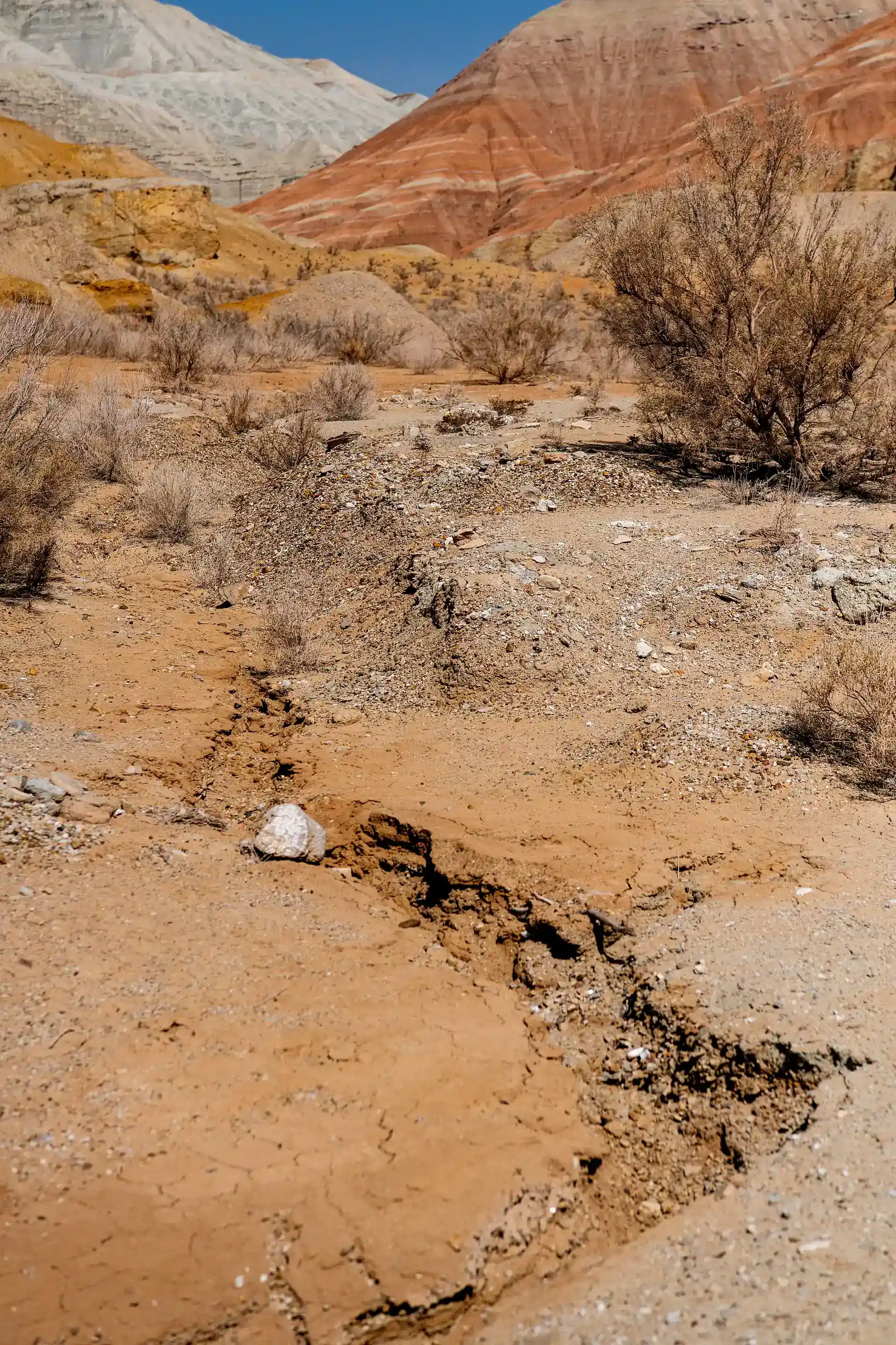 Narrow eroded clay gully in the Aktau Mountains with pale and rust-colored walls.