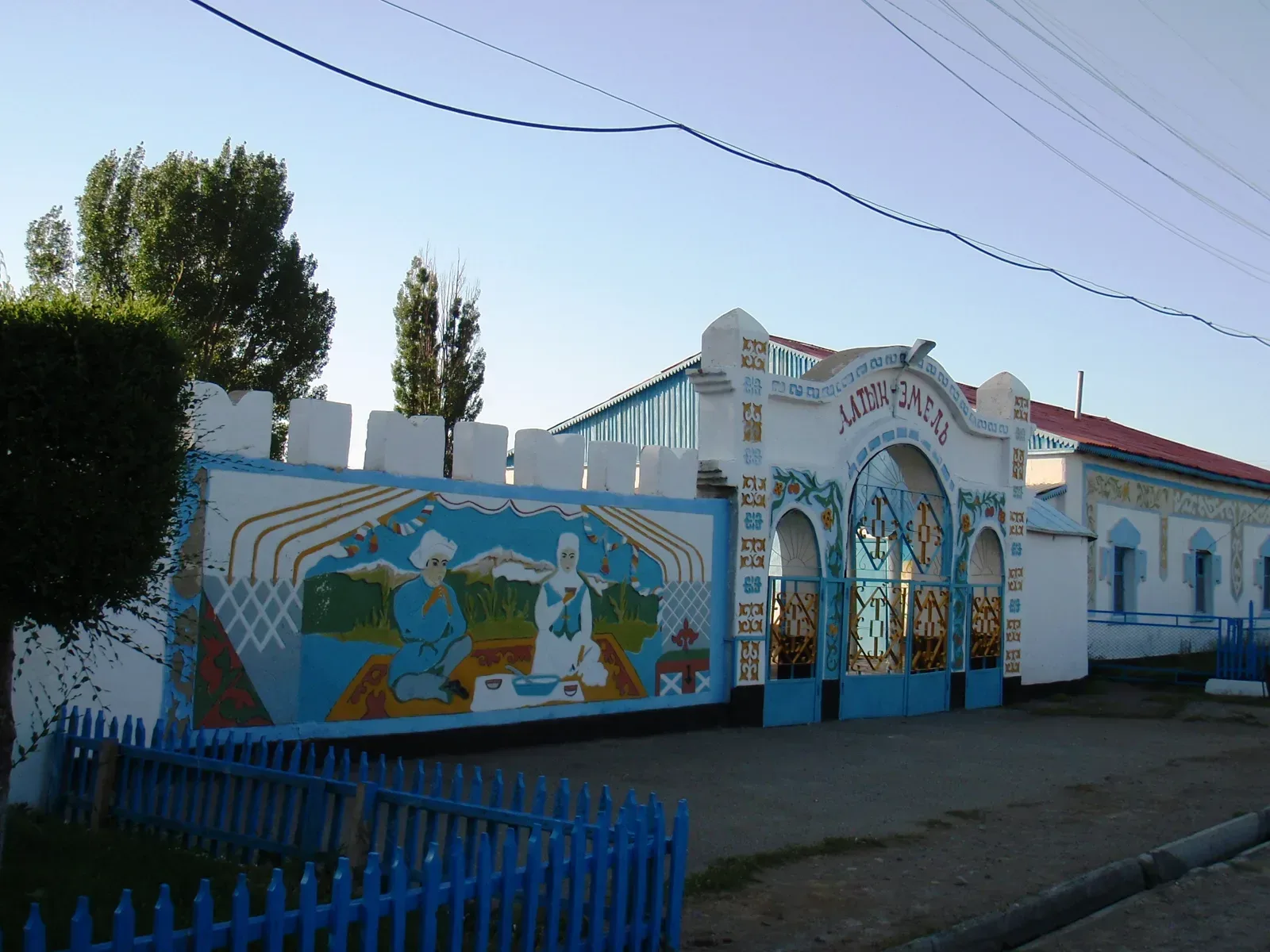 Context near Aktau White Mountains: Painted gateway building at Basshi village entrance bearing the Altyn-Emel name in Kazakh script.