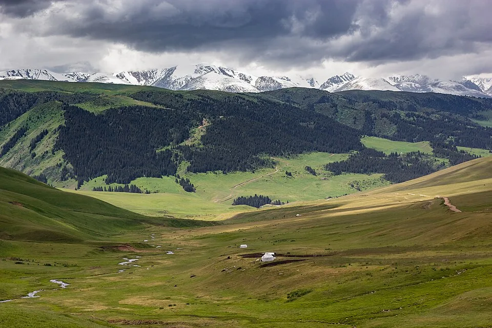 Single yurt on the Assy Plateau spring pasture with low hills beyond the camp.