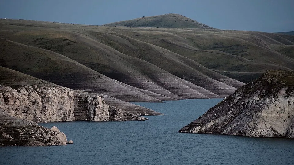 Bartogay Reservoir basin seen from the dam area with mountains beyond the water.