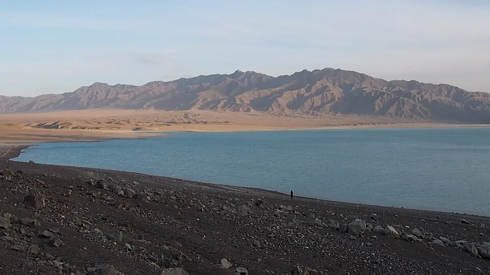 Open shoreline of Bartogay Reservoir with pale water below dry steppe hills.