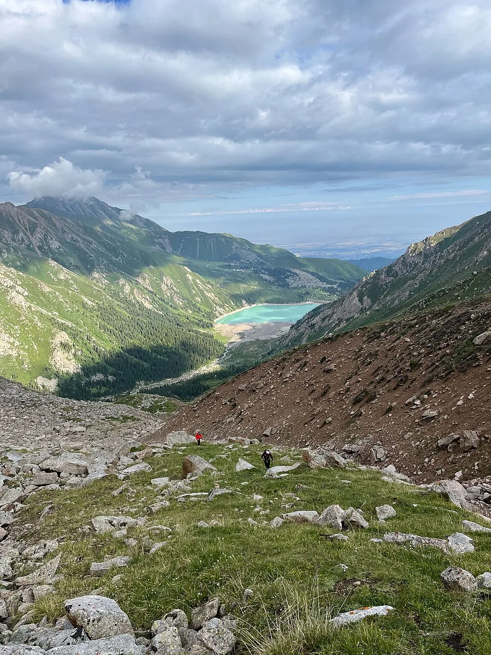 Big Almaty Lake seen from a mountain overlook with steep grey slopes around the water.
