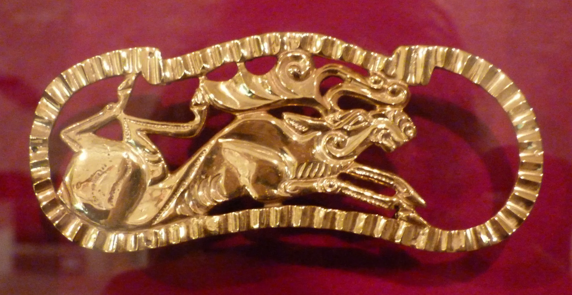 Gold elk plaque from the Issyk burial mound photographed in a museum display.
