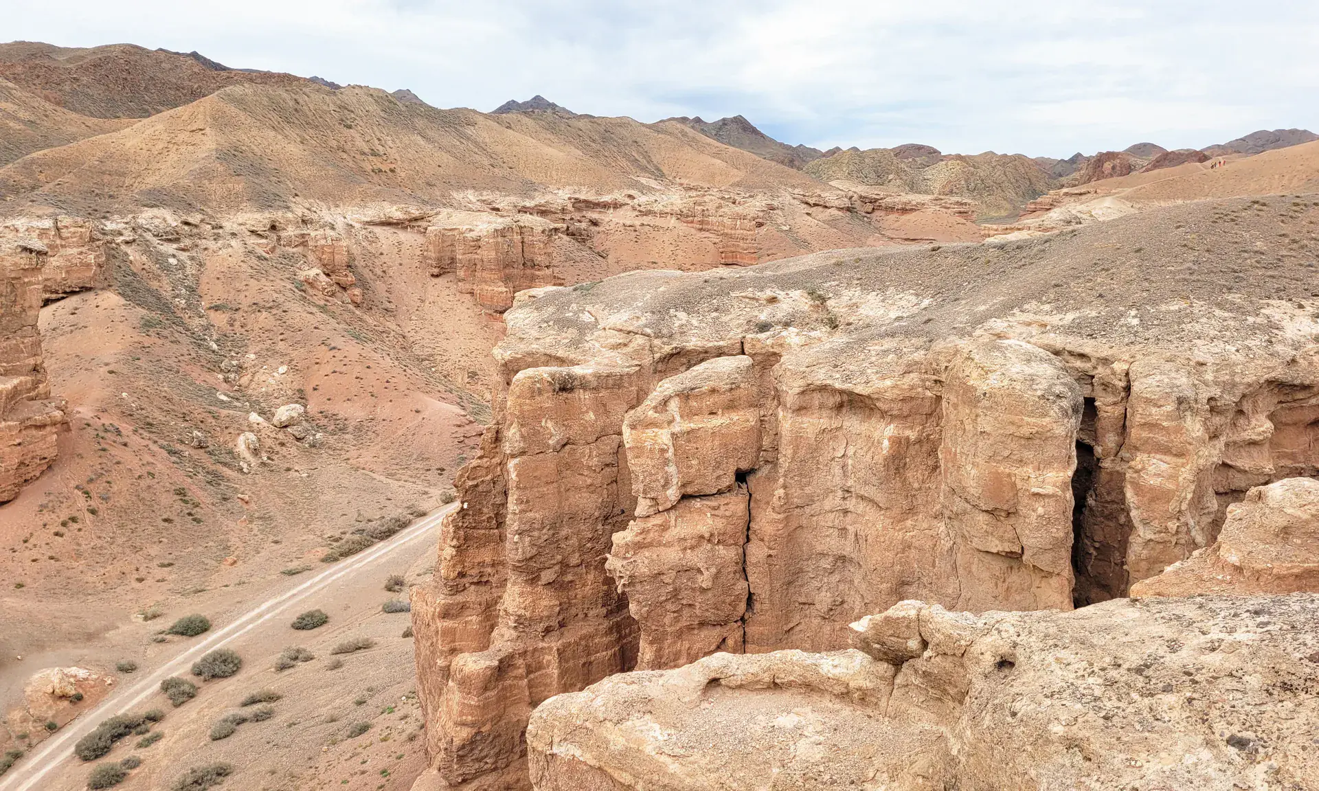 Layered Charyn Canyon cliffs rising above a pale trail on the canyon floor.