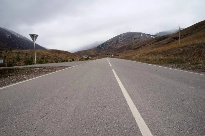 Dirt road following the Kaskelen Gorge floor between dry grassy slopes.
