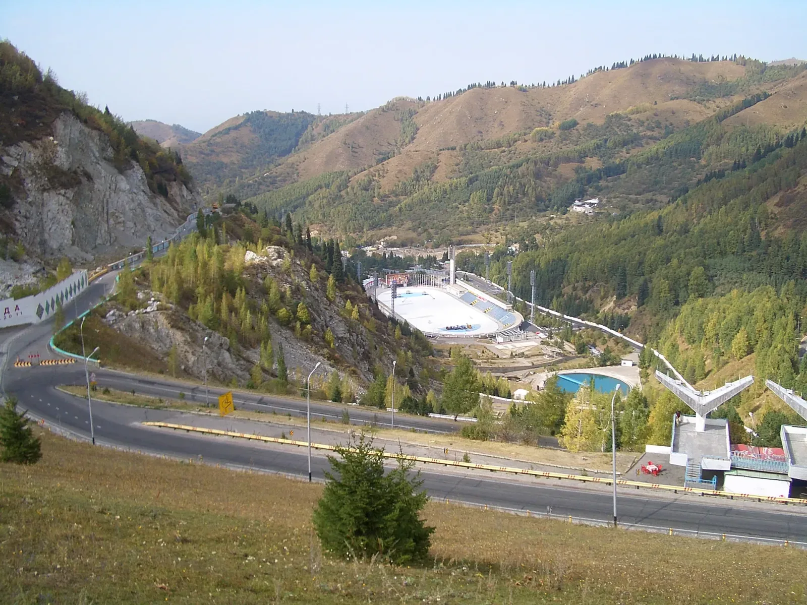 Context near Eco Post Trailhead: Medeu ice rink viewed from the anti-mudflow dam road above the stadium in the mountain valley.