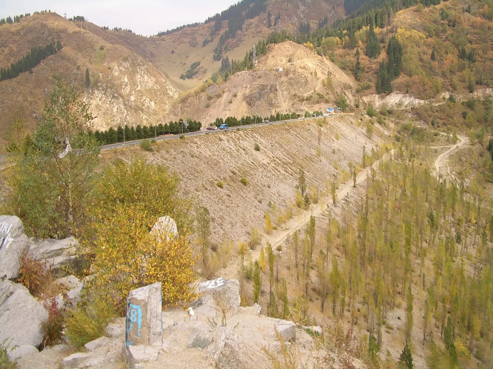 Context near Glacier Terminus Viewpoint 3 400 M: Upper Shymbulak valley with rocky gorge walls and a dirt track leading toward the higher glacier route.