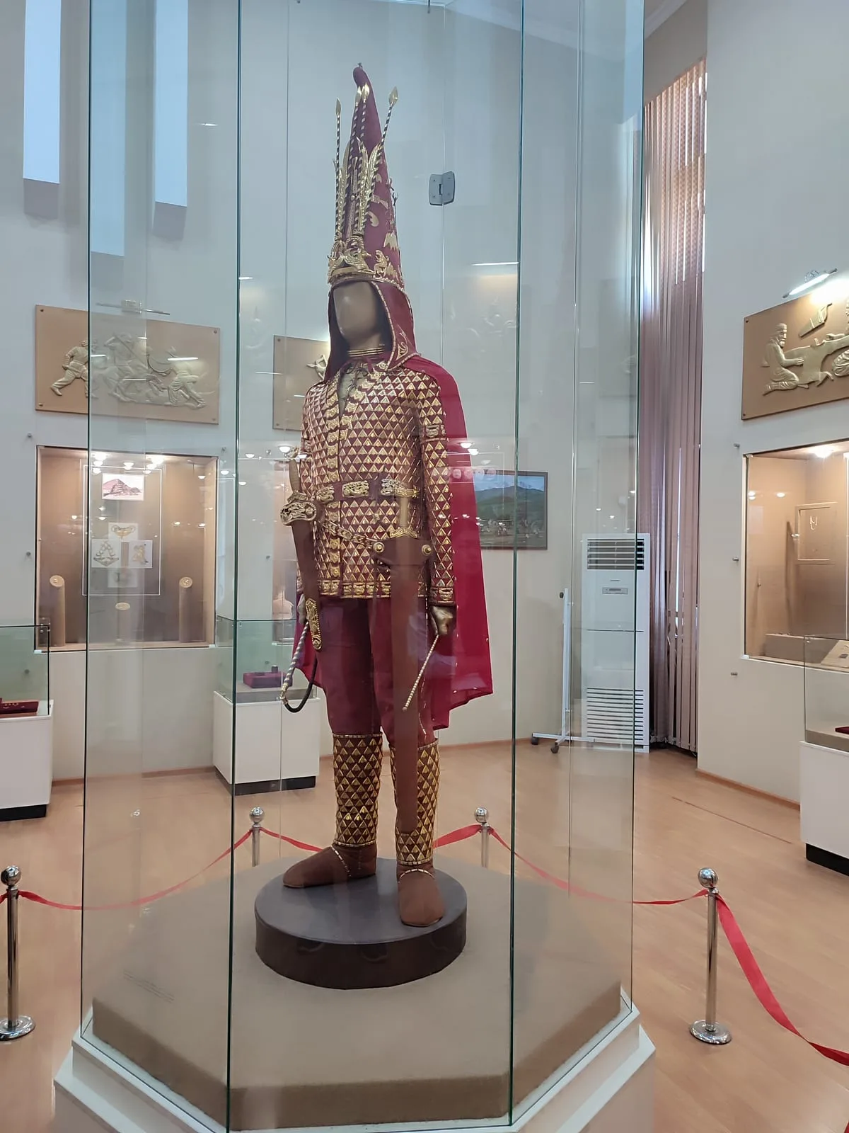 Context near Issyk Historical Archaeological Museum: Replica of the Golden Man warrior displayed at the Esik museum, with gold costume plates and tall headgear.
