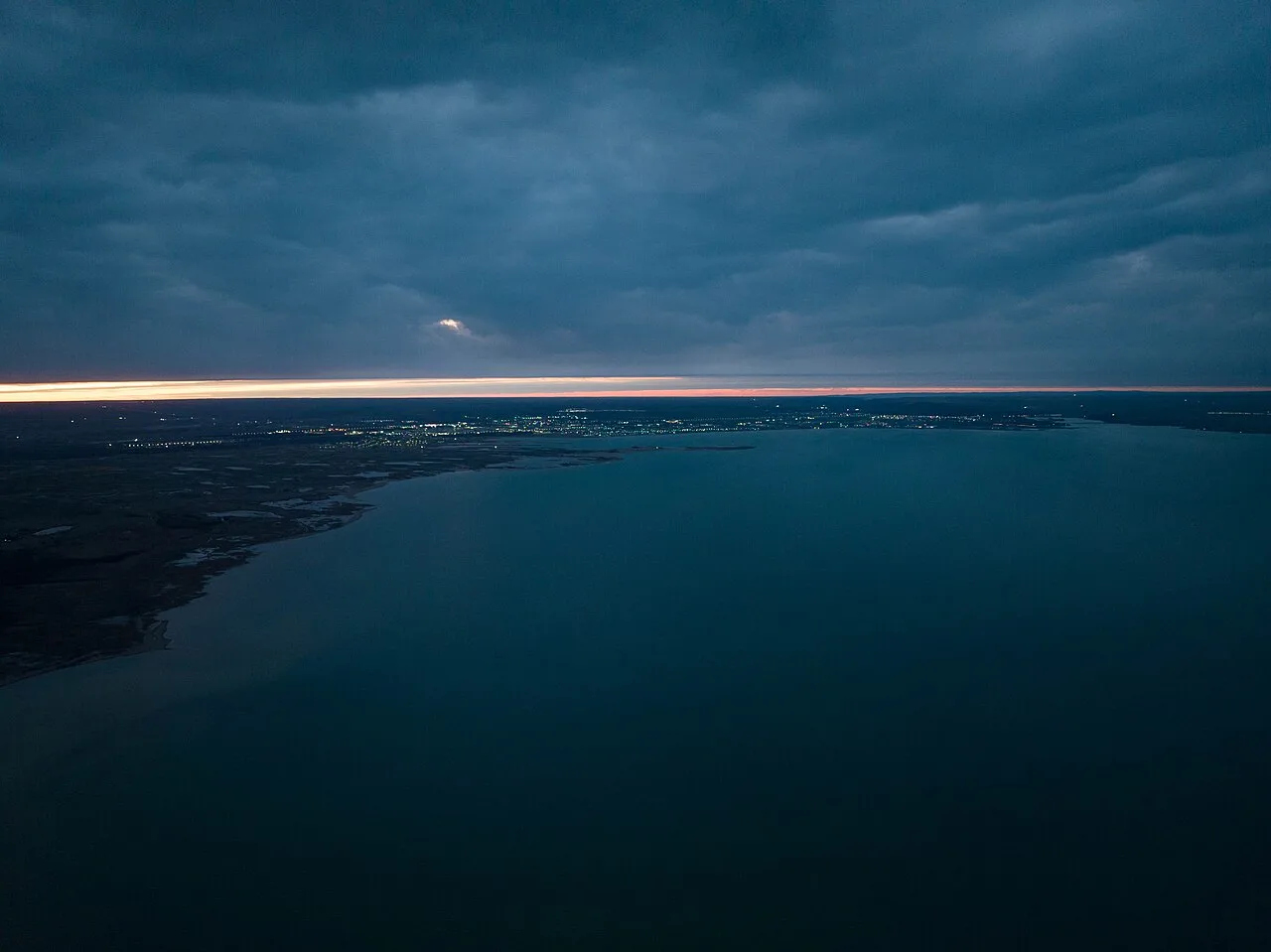 Aerial sunset view over Konaev and the Kapchagai reservoir edge near the Ili River dam crossing.
