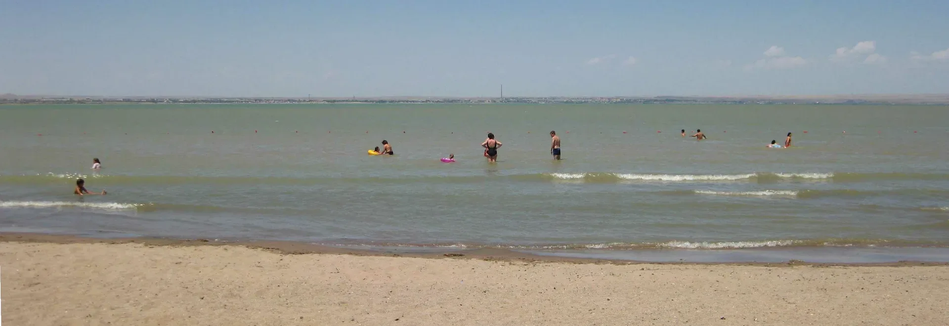 Shore of Kapchagay Water Reservoir in Almaty province Kazakhstan, wide flat water with dry steppe bank