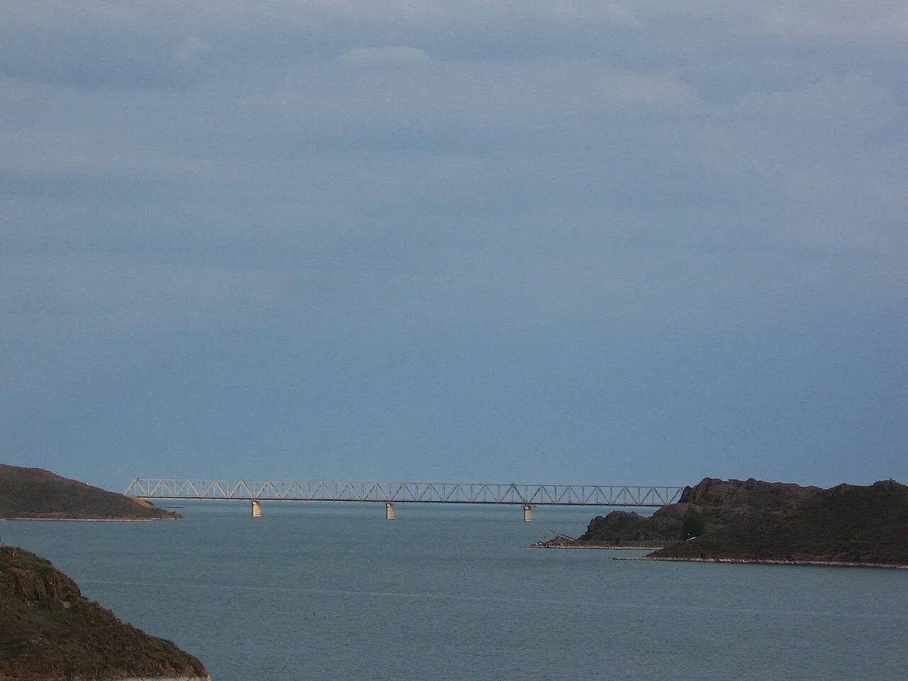Reservoir-side road through dry steppe near Kapchagai, matching the open A-3 crossing landscape.