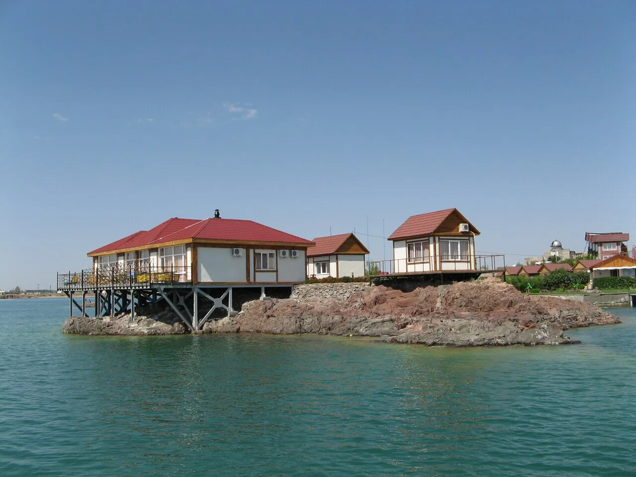 Kapchagai reservoir shoreline with calm water and low dry banks under an open sky.
