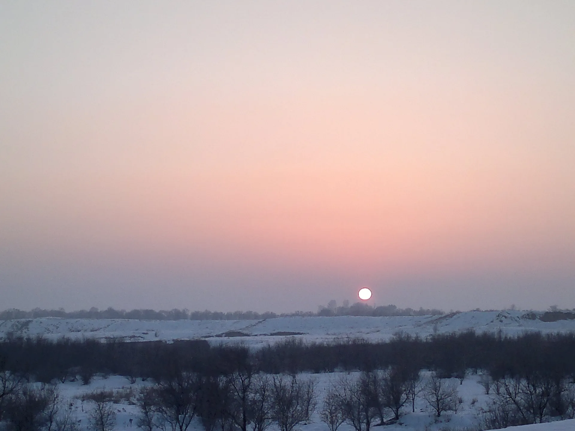 Karasay District street scene near Kaskelen, with low buildings and foothill terrain beyond the town edge.