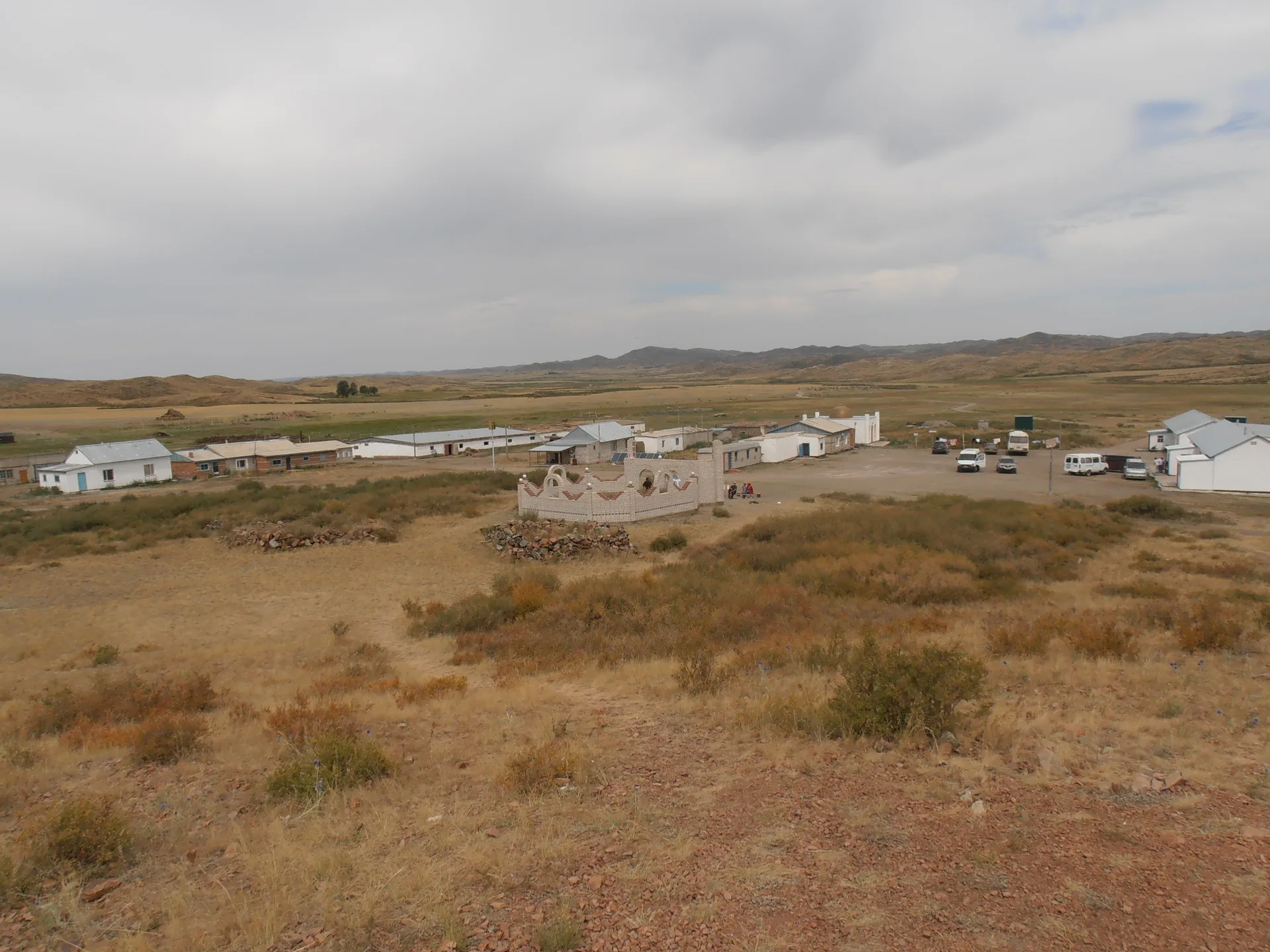 Rear wall and rounded dome of Bayanbai mausoleum, showing mudbrick construction in an open steppe setting.