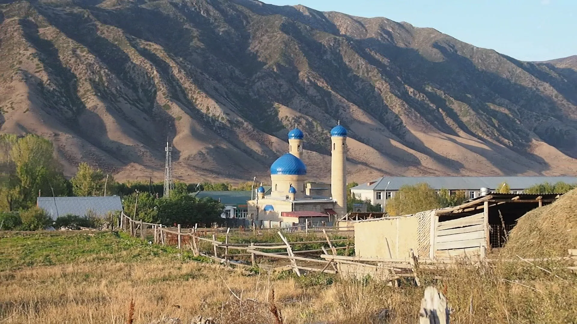 Saty village in the Kegen district valley, with houses spread across flat ground below mountain slopes.