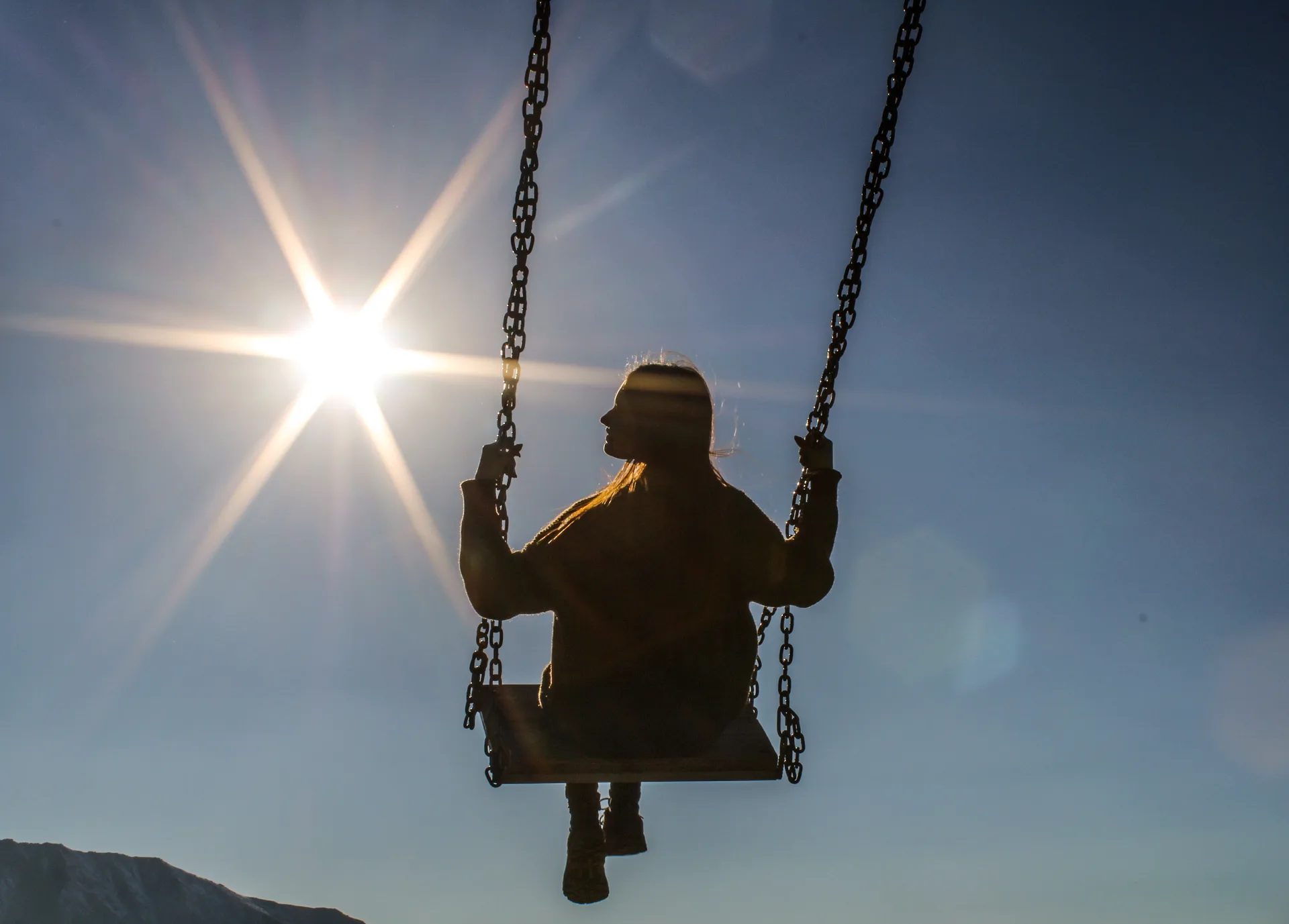 Metal swing on the Kimasar ridge route toward Furmanov Peak, set on an open mountain clearing.