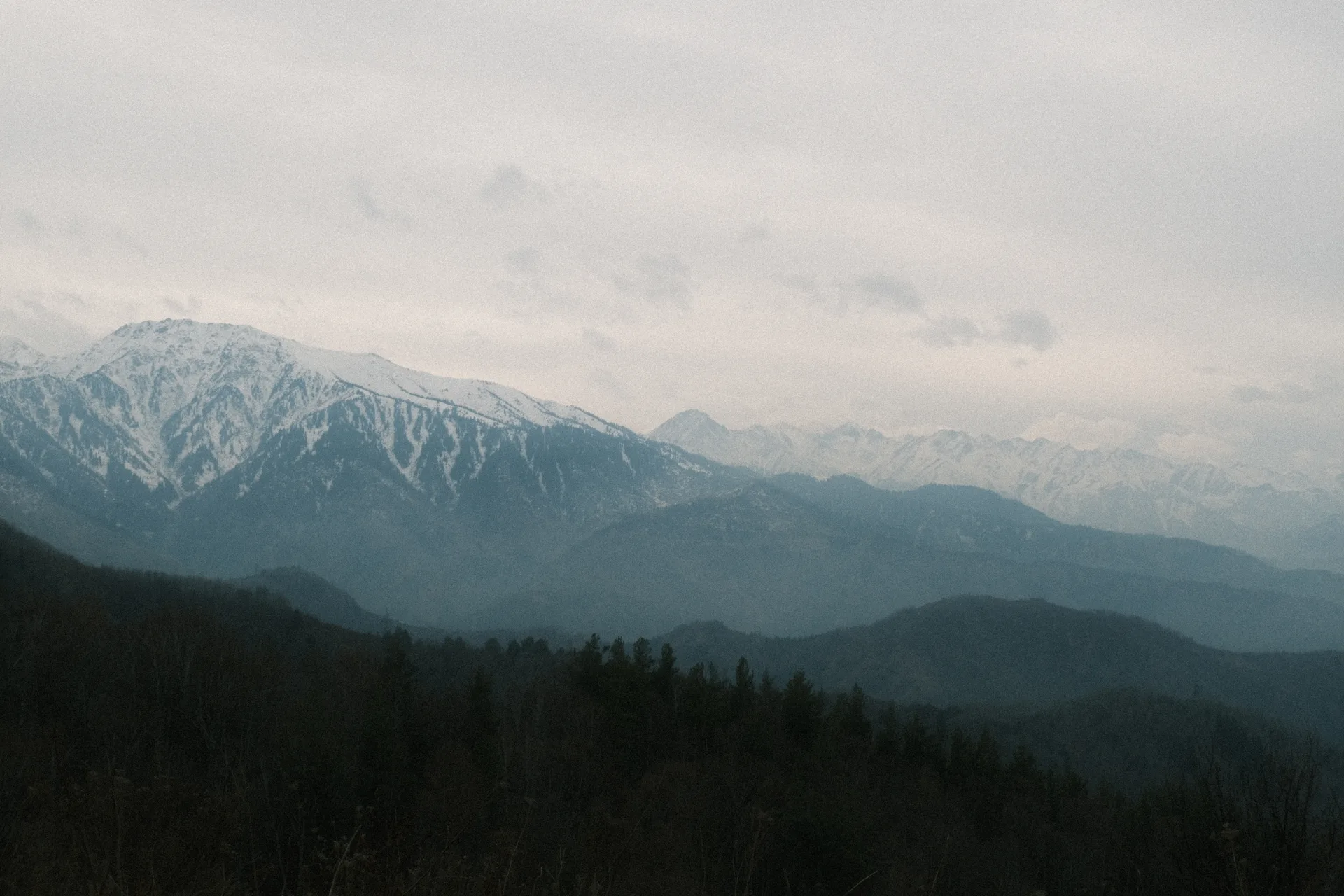 Kim Asar viewpoint above Almaty, with open ridge grass and the city plain visible beyond the mountainside.