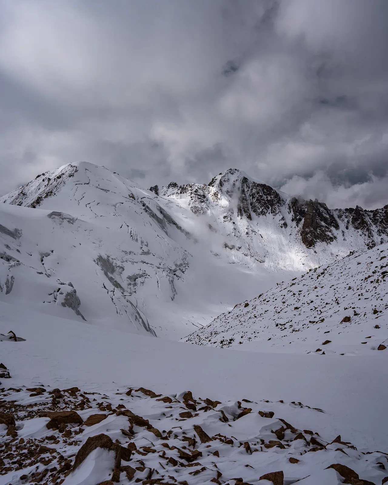 Context near Kimasar Ridge The Swing: Rocky high-mountain route looking toward the Tuyuksu Glacier below clouded peaks.