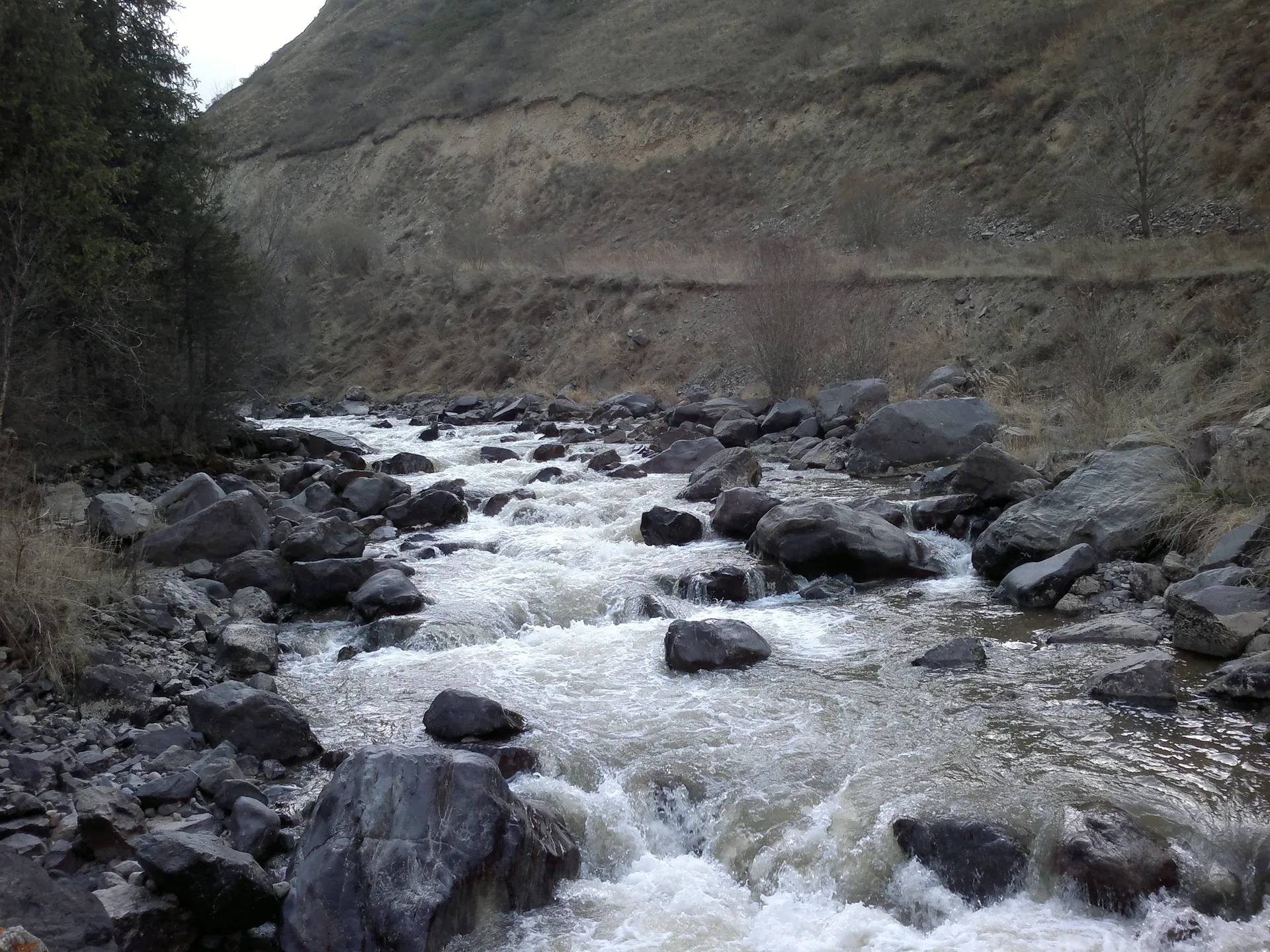 Turgen River valley road leading toward the Bear Waterfall parking area in green foothills.
