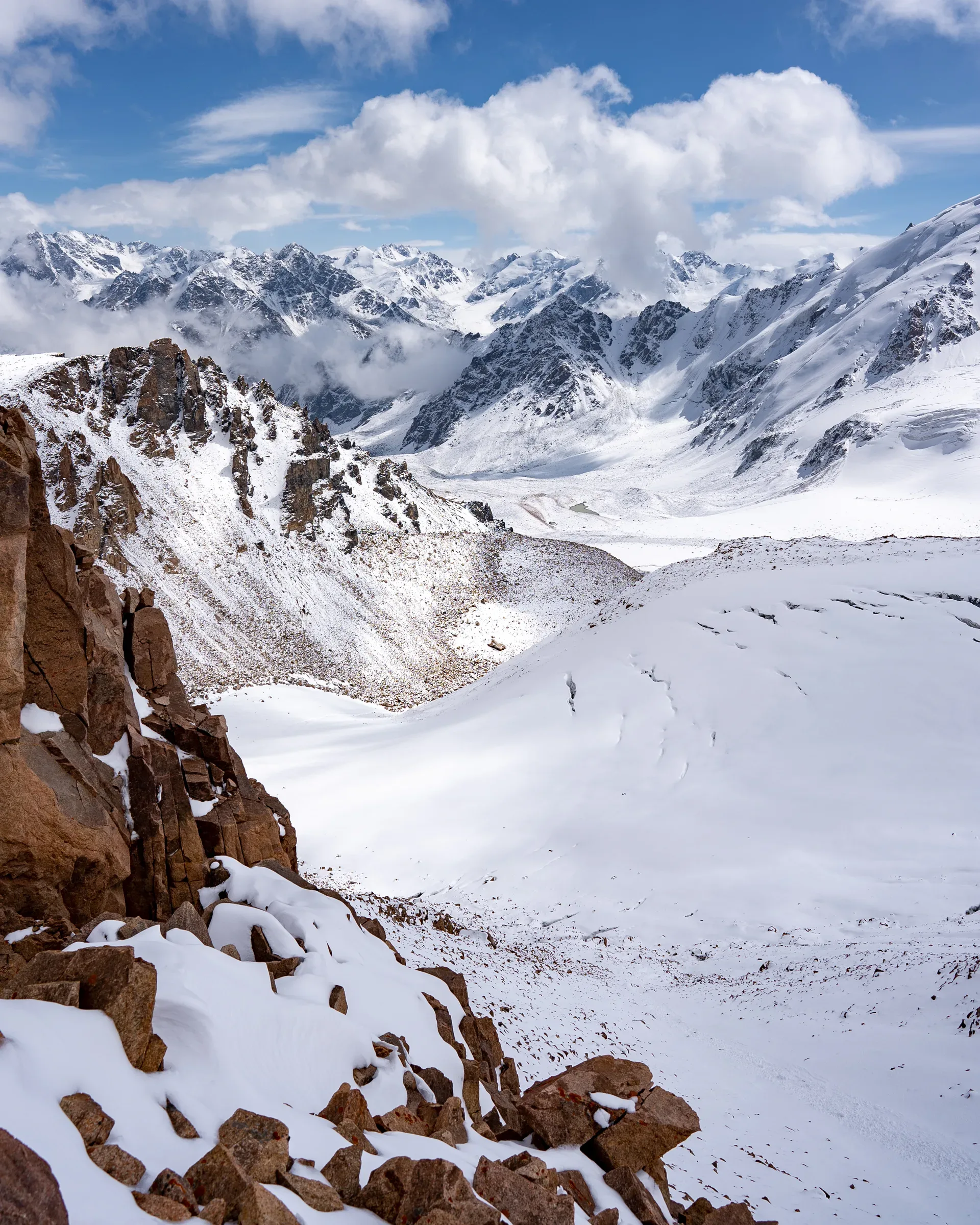View from Tuyuksu Pass toward the Tourists Gorge, open alpine terrain with rocky ridge lines descending into a glacial valley