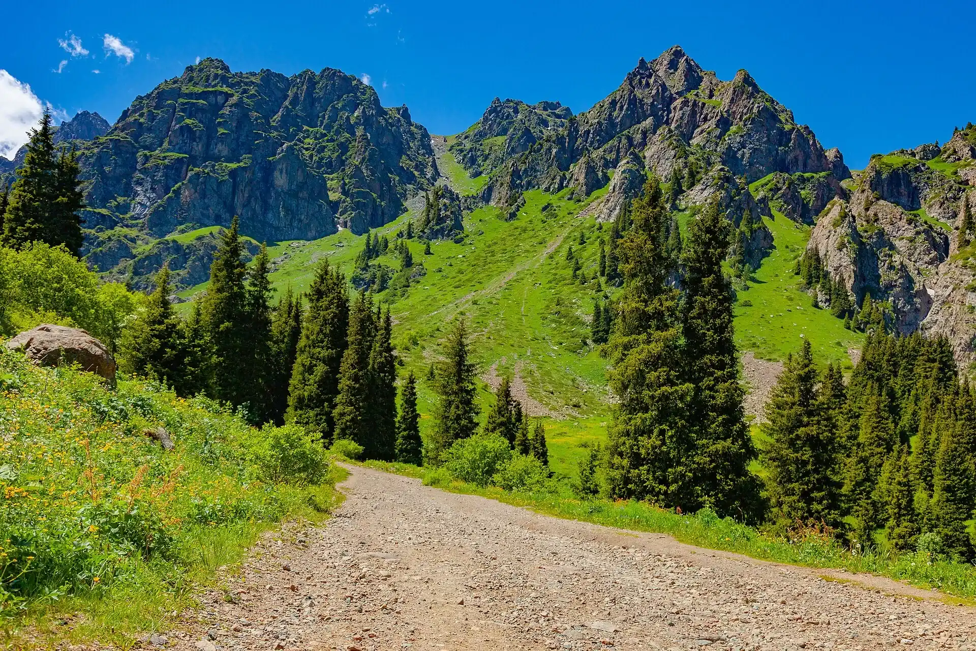 Dirt mountain road winding through arid foothill terrain on the approach south of Shelek.