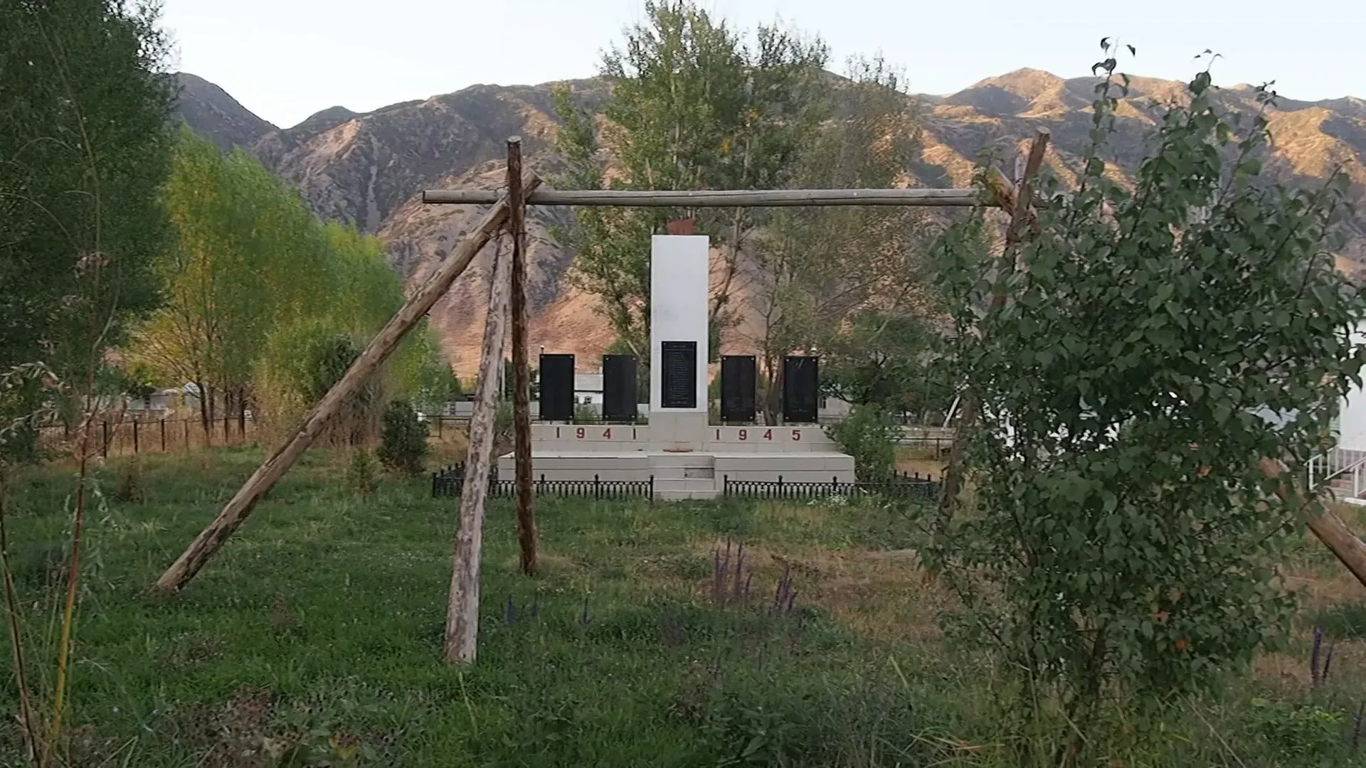 Saty village in the Almaty Region of Kazakhstan seen from the valley road, with low houses and mountain slopes rising above the settlement.