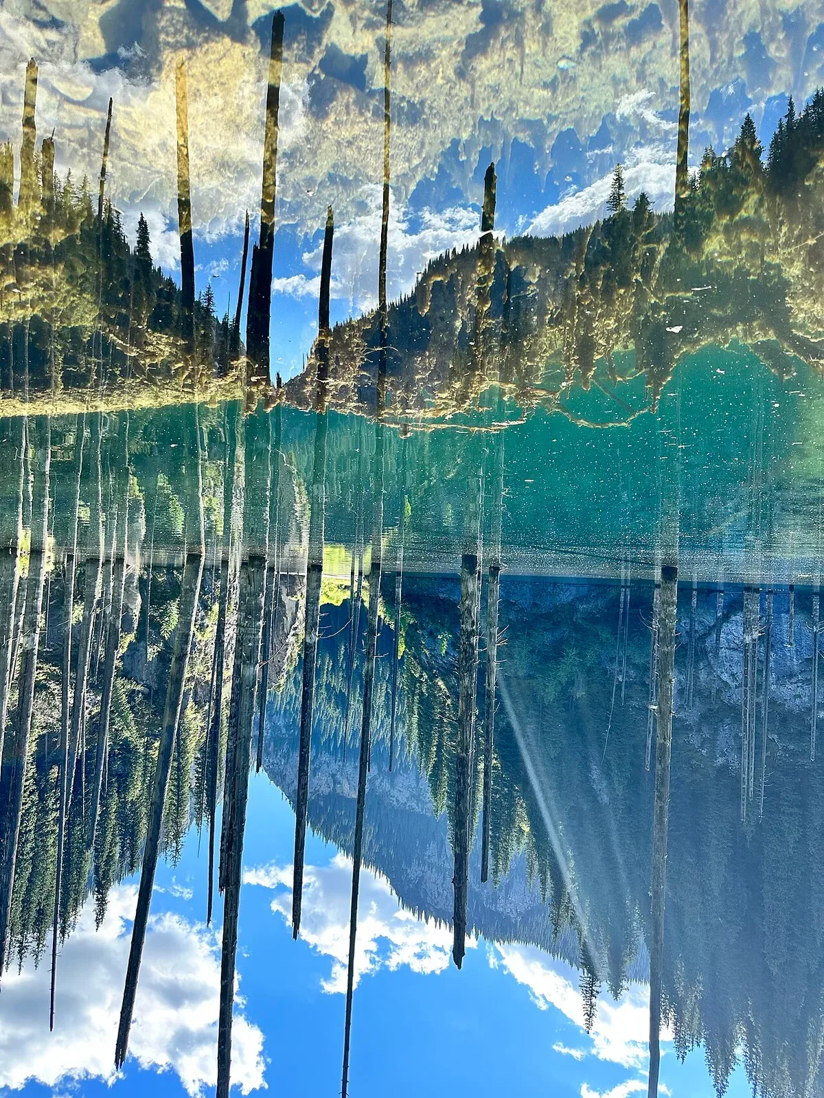 Context near Saty Village: Rocky Kaindy approach stream and forested gorge terrain similar to the rough track before the parking clearing.