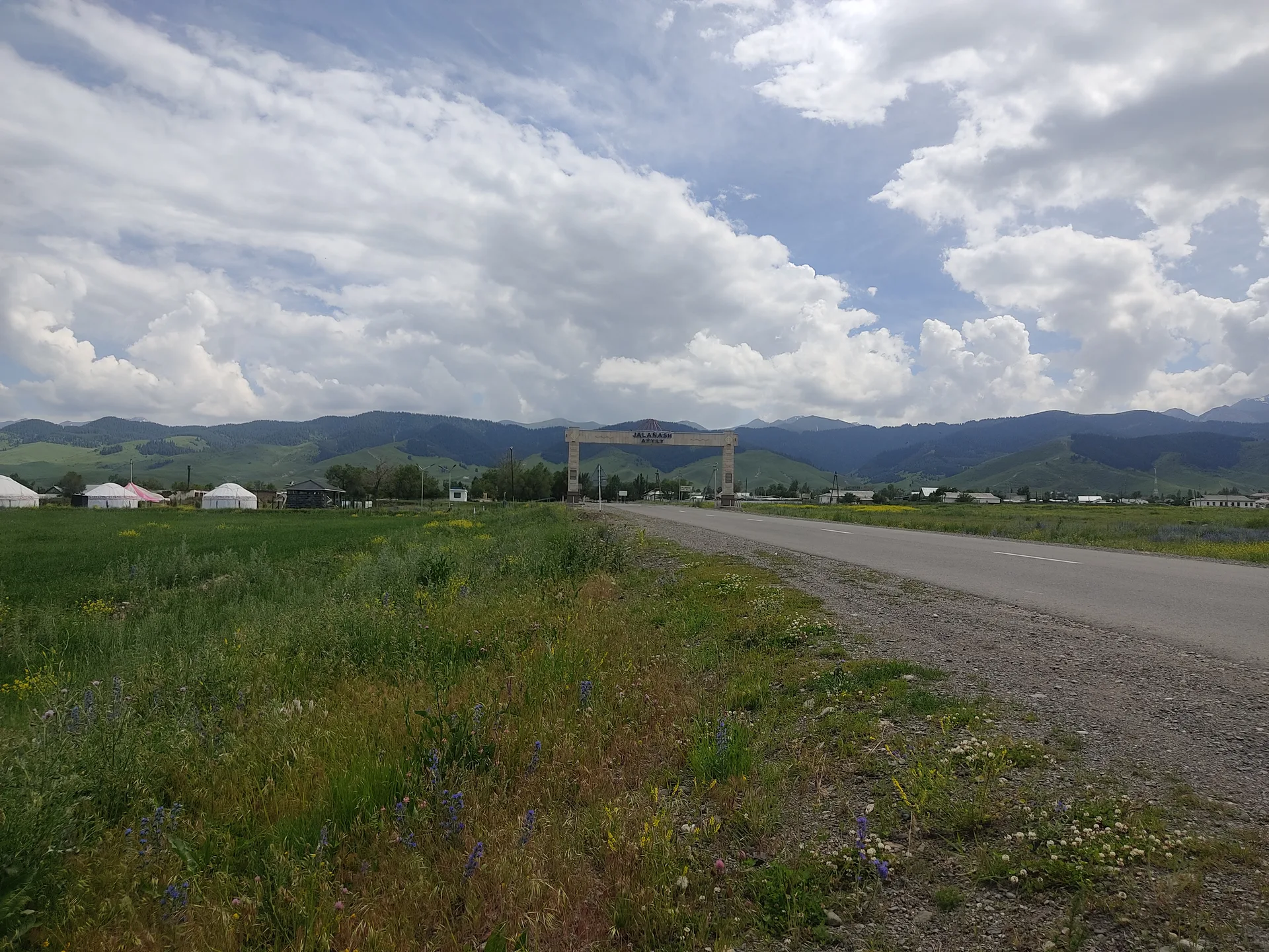 Open highway corridor between Shelek and Kegen with mountain foothills beyond the road.