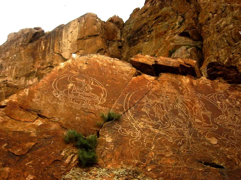 Seated Buddhist figures carved into sandstone cliffs above the Ili River at Tamgaly-Tas.