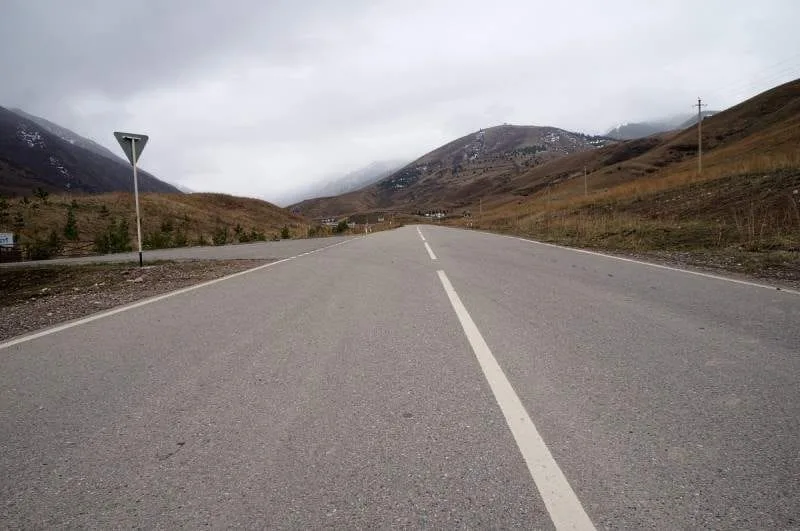 Context near Uy Tas Glacial Erratic 2 000 M: Dirt road following the Kaskelen Gorge floor between dry grassy slopes.