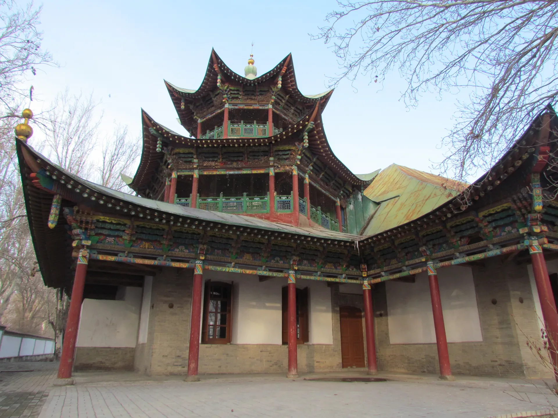 Zharkent Mosque wooden facade showing carved decorative panels, curved roof eaves, and open gallery columns along the prayer hall entrance