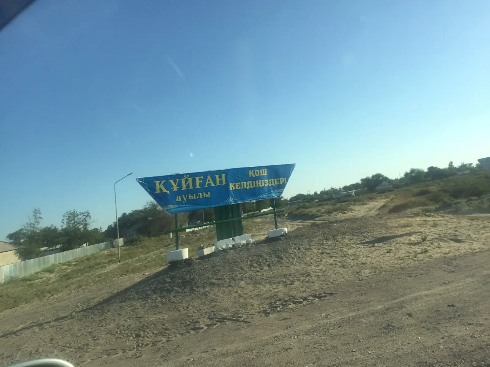 Context near Zharkent Mosque: Small agricultural settlement on the Ile River bank with mud-brick buildings and reed-lined water nearby.