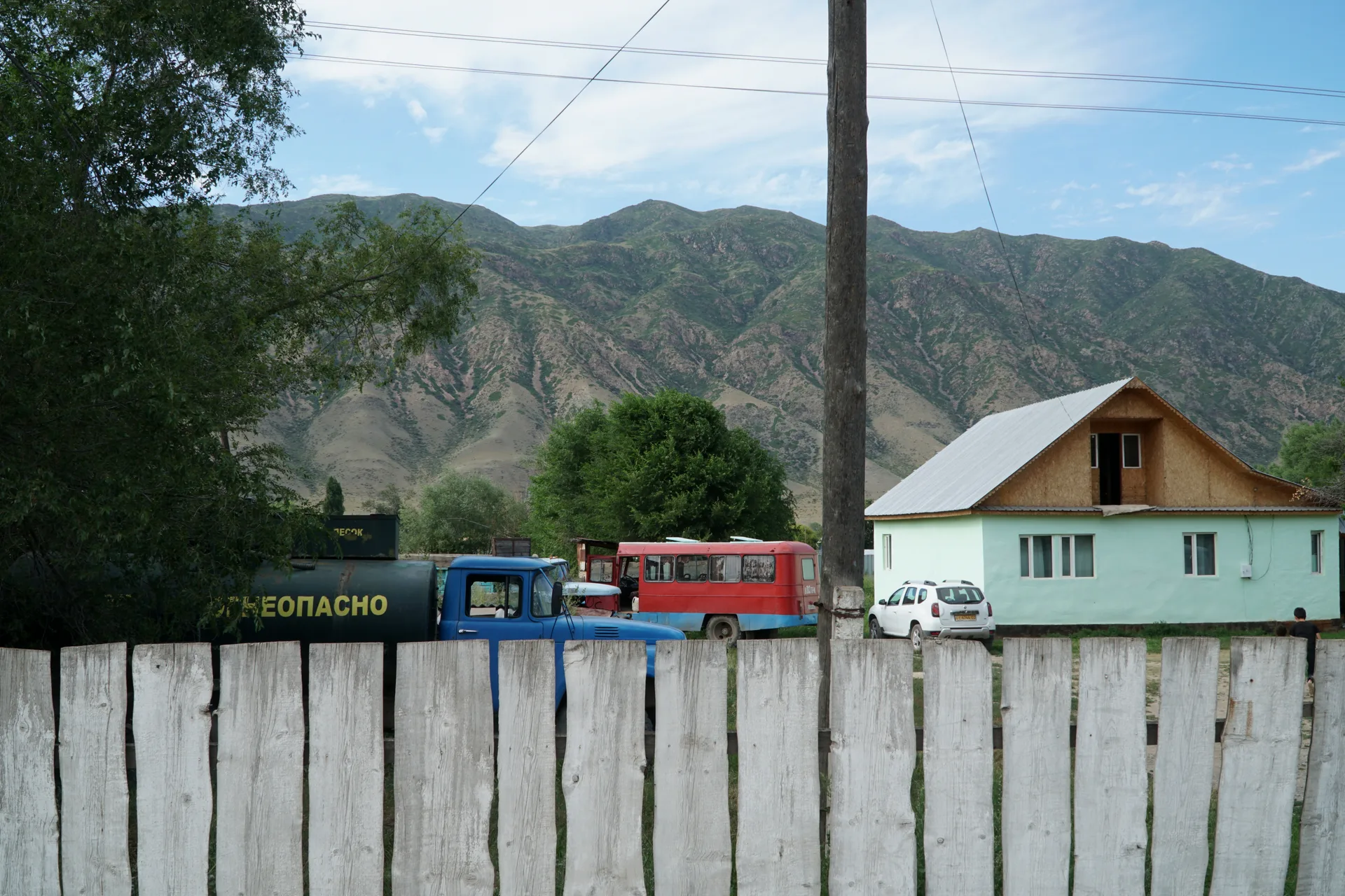 Open alpine meadow in the Saty region, Kazakhstan, with mountain slopes above the treeline visible in summer grazing season.