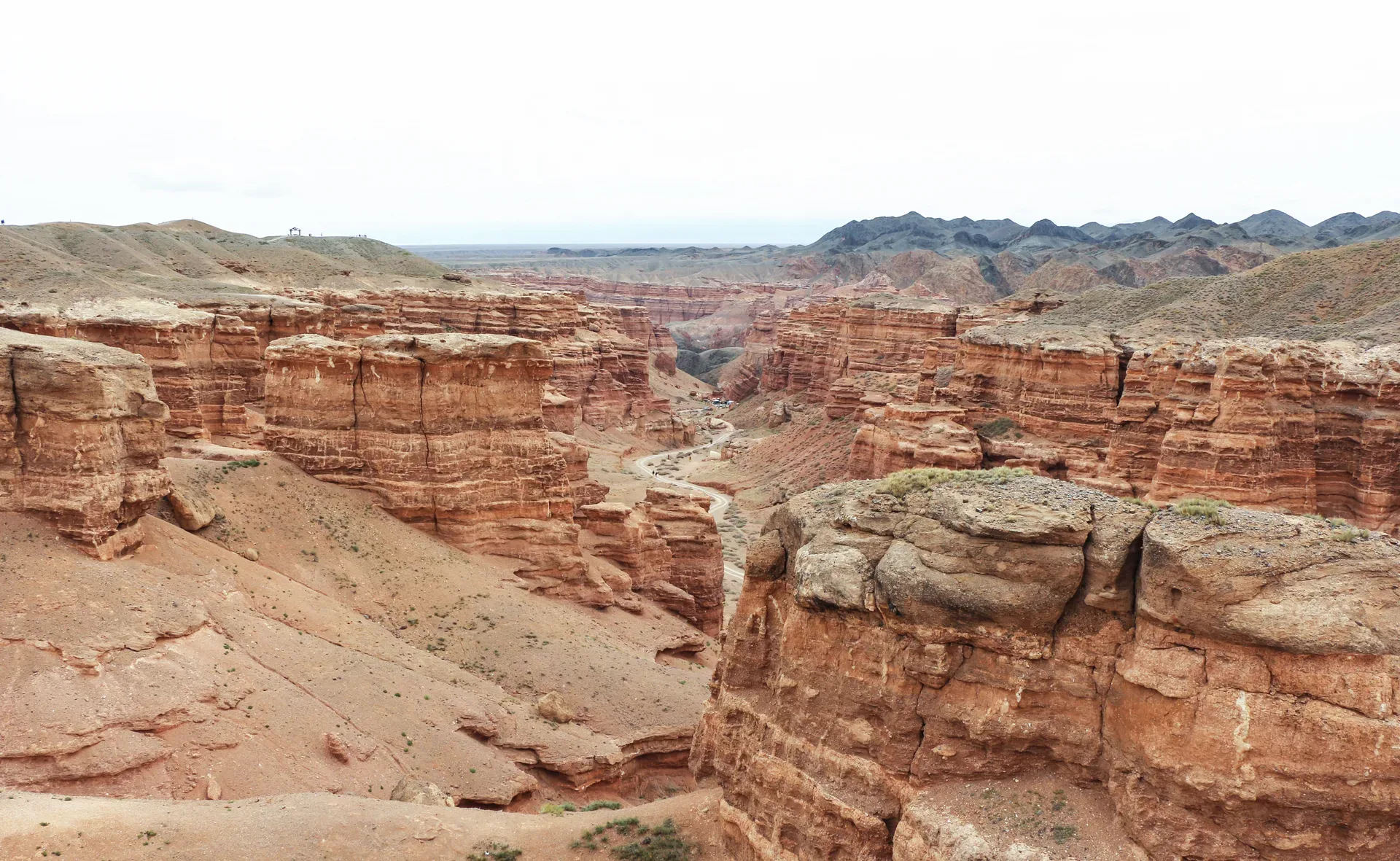 Eroded red and orange sandstone formations in Charyn Canyon's Valley of Castles under a blue sky.