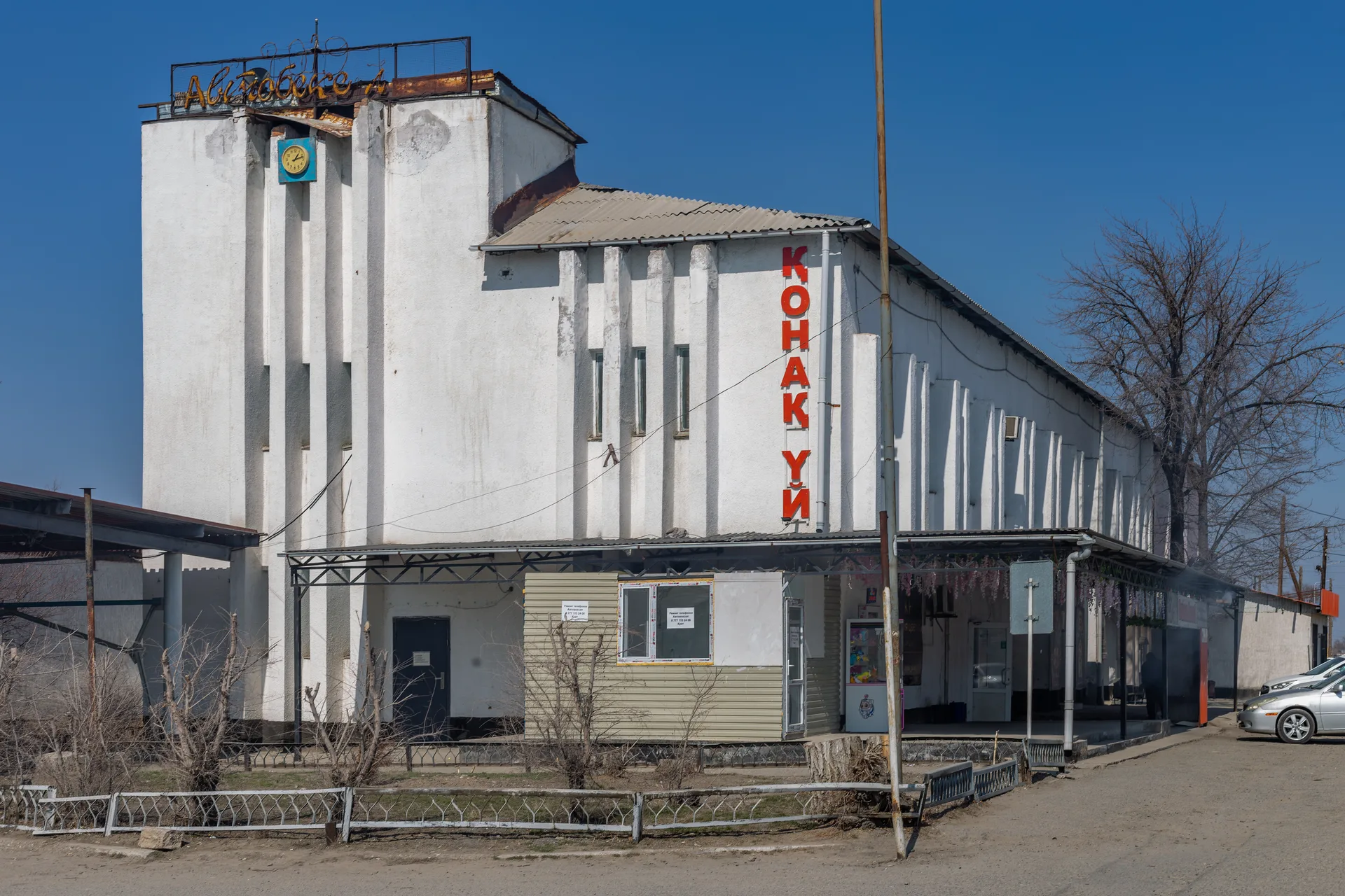 Ushtobe bus station, a single-storey Soviet modernist concrete building with large windows, on a quiet street in Karatal District, Kazakhstan