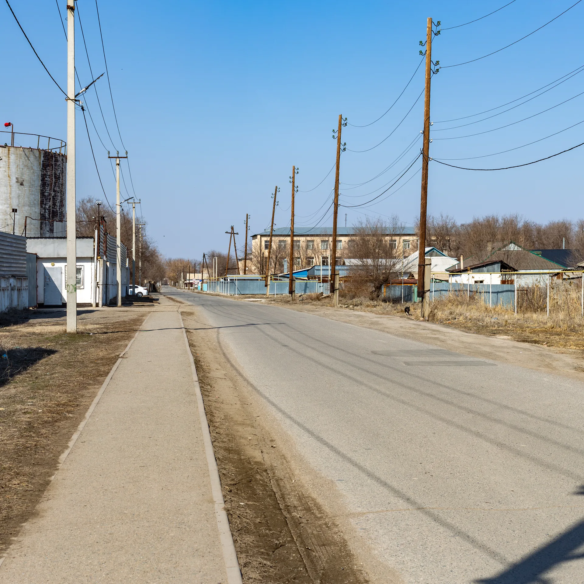 Gagarin Street in Bastobe district of Ushtobe, Kazakhstan, lined with low houses and a wide unpaved verge under a clear sky