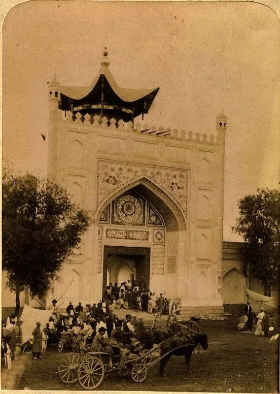 Black-and-white photograph from 1890–1900 showing the ornate carved wooden gateway of the Taranchi Mosque in Jarkent, with decorative pointed arch framing